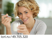 happy young woman eating yogurt in kitchen. Стоковое фото, агентство Ingram Publishing / Фотобанк Лори