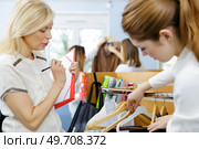 young woman choosing clothes on a rack in a showroom. Стоковое фото, агентство Ingram Publishing / Фотобанк Лори