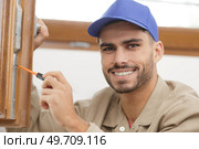 young man contractor screwing window handle mechanism. Стоковое фото, агентство Ingram Publishing / Фотобанк Лори