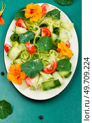 Pansy salad with cucumber, cherry tomatoes and nasturtium served on plate. Top view. Vegan food.. Vegetable dietary salad with nasturtium flowers. Стоковое фото, агентство Ingram Publishing / Фотобанк Лори