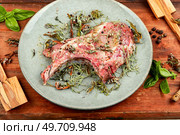 Uncooked pork steak Tomahawk marinated in spicy herbs with ingredients for grilling on wooden background.. Raw barbecue Tomahawk steak. Стоковое фото, агентство Ingram Publishing / Фотобанк Лори