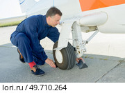 worker checking undercarriage of plane. Стоковое фото, агентство Ingram Publishing / Фотобанк Лори