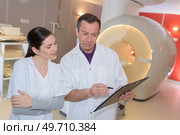 doctor standing arms crossed by patient lying on mri machine. Стоковое фото, агентство Ingram Publishing / Фотобанк Лори