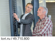 Customer with salesman looking at shutters. Стоковое фото, агентство Ingram Publishing / Фотобанк Лори