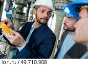 worker holding multimeter and looking accusingly at colleagues. Стоковое фото, агентство Ingram Publishing / Фотобанк Лори