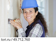 happy woman repairs wall with spackling paste. Стоковое фото, агентство Ingram Publishing / Фотобанк Лори