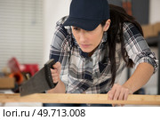 focused woman using handsaw. Стоковое фото, агентство Ingram Publishing / Фотобанк Лори