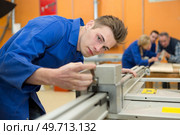 young man cutting in a factory. Стоковое фото, агентство Ingram Publishing / Фотобанк Лори