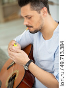 a man smokes while playing guitar. Стоковое фото, агентство Ingram Publishing / Фотобанк Лори