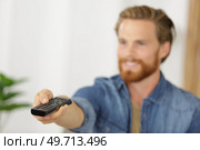 man with remote control switches channels on the tv. Стоковое фото, агентство Ingram Publishing / Фотобанк Лори