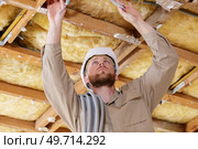 tradesman installing electric cabling around ceiling joists. Стоковое фото, агентство Ingram Publishing / Фотобанк Лори
