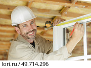 male builder measuring a window. Стоковое фото, агентство Ingram Publishing / Фотобанк Лори