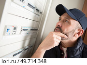 man pondering the fuses in a circuit breaker cabinet. Стоковое фото, агентство Ingram Publishing / Фотобанк Лори
