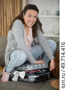 young woman packing suitcase trying to close it. Стоковое фото, агентство Ingram Publishing / Фотобанк Лори