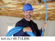 portrait of builder holding reel of blue cable. Стоковое фото, агентство Ingram Publishing / Фотобанк Лори