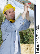 male builder in overalls assembles a window. Стоковое фото, агентство Ingram Publishing / Фотобанк Лори