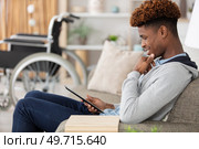 man relaxing on sofa with tablet near wheelchair. Стоковое фото, агентство Ingram Publishing / Фотобанк Лори