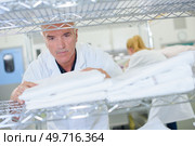 Senior man stacking clean laundry on shelf. Стоковое фото, агентство Ingram Publishing / Фотобанк Лори