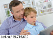 Father cuddling boy looking at computer. Стоковое фото, агентство Ingram Publishing / Фотобанк Лори