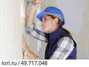 female builder removing wallpaper with scraper. Стоковое фото, агентство Ingram Publishing / Фотобанк Лори