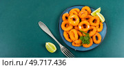 Baked breaded calamari rings served with lime. Copy space. Deep fried squid rings, space for text. Стоковое фото, агентство Ingram Publishing / Фотобанк Лори