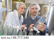 smiling young woman in protective working wear checking bottles. Стоковое фото, агентство Ingram Publishing / Фотобанк Лори