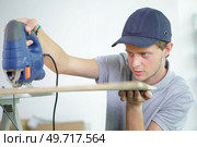 Young man using electric jigsaw. Стоковое фото, агентство Ingram Publishing / Фотобанк Лори