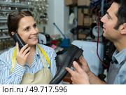 couple working in cobblers shop woman on telephone. Стоковое фото, агентство Ingram Publishing / Фотобанк Лори