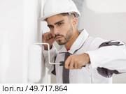 man constructor in helmet plastering wall with rolle. Стоковое фото, агентство Ingram Publishing / Фотобанк Лори