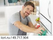 portrait of man spraying product to clean oven. Стоковое фото, агентство Ingram Publishing / Фотобанк Лори
