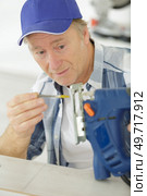 carpenter changes the nozzle in an electric jigsaw. Стоковое фото, агентство Ingram Publishing / Фотобанк Лори