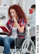 disabilty and handicap young disabled woman on wheelchair reads book. Стоковое фото, агентство Ingram Publishing / Фотобанк Лори