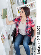 young disabled woman reaching out for blanket at shelf. Стоковое фото, агентство Ingram Publishing / Фотобанк Лори