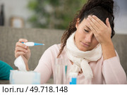 lady holding a thermometre and feeling temperature of her forehead. Стоковое фото, агентство Ingram Publishing / Фотобанк Лори