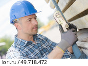 Man attaching load with ratchet strap. Стоковое фото, агентство Ingram Publishing / Фотобанк Лори