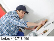 man removing masking tape from skirting board. Стоковое фото, агентство Ingram Publishing / Фотобанк Лори