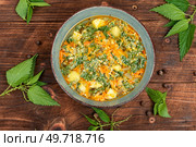 Vegan nettle soup on old rustic wooden table. Top view.. Vegan seasonal nettle soup. Стоковое фото, агентство Ingram Publishing / Фотобанк Лори