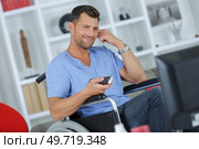 happy handicapped man watching television in living room. Стоковое фото, агентство Ingram Publishing / Фотобанк Лори