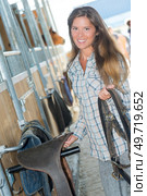 Lady in riding stables picking up tack. Стоковое фото, агентство Ingram Publishing / Фотобанк Лори