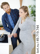 pregnant woman with backache standing in the kitchen. Стоковое фото, агентство Ingram Publishing / Фотобанк Лори