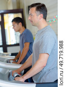 Two men using aerobic exercise machines. Стоковое фото, агентство Ingram Publishing / Фотобанк Лори
