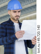 repairman or builder in helmet working with drawings. Стоковое фото, агентство Ingram Publishing / Фотобанк Лори