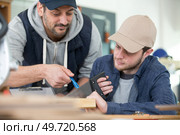 young male apprentice using saw under supervision. Стоковое фото, агентство Ingram Publishing / Фотобанк Лори