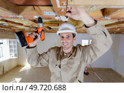 man using cordless drill on wooden ceiling joist. Стоковое фото, агентство Ingram Publishing / Фотобанк Лори