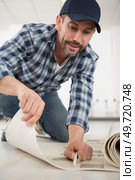 man is cutting linoleum flooring. Стоковое фото, агентство Ingram Publishing / Фотобанк Лори