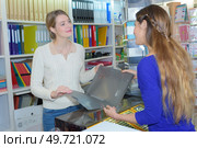 Woman looking at folder in stationery shop. Стоковое фото, агентство Ingram Publishing / Фотобанк Лори