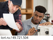 workmen follow instructions for the assembly of an electrical appliance. Стоковое фото, агентство Ingram Publishing / Фотобанк Лори