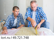 carpenter teaching apprentice how to measure wood. Стоковое фото, агентство Ingram Publishing / Фотобанк Лори