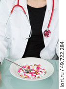 bowl of multicolored tablets in front of medical worker. Стоковое фото, агентство Ingram Publishing / Фотобанк Лори