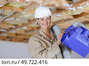 female worker fitting ventilation system in property under renovation. Стоковое фото, агентство Ingram Publishing / Фотобанк Лори